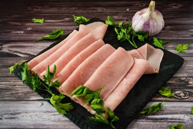 Köy tahtasında sarımsaklı jambon ya da prosciutto cotto kaplı siyah bir levha üzerinde zarif bir düzenleme..