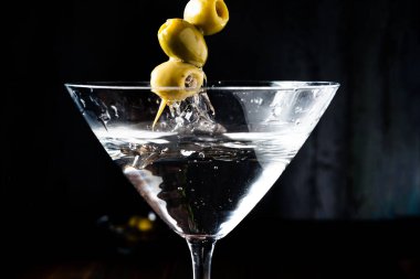 Scooping the olives out of the dry martini glass. Vertical orientation,