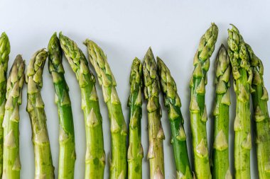 Beyaz arka planda izole edilmiş bir grup çiğ yeşil kuşkonmaz..