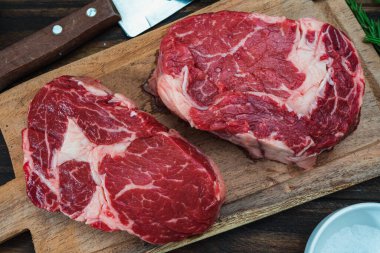 Tahta bir tahtanın üzerinde iki çiğ kaburganın yakın çekimi. Genel Görünüm.