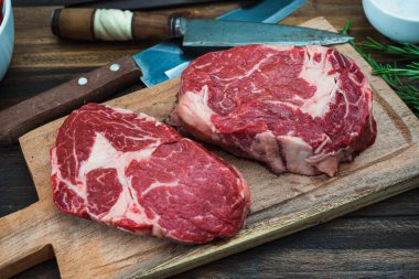 Kırsal ahşap bir kesme tahtasının üzerinde iki çiğ kaburga kemiğinin yakın çekimi. Yemek konsepti. Genel Görünüm.