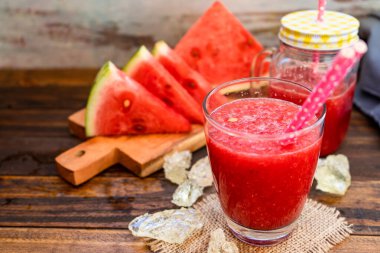 Arka planda soğuk karpuz smoothie ile büyük bir bardak ve bazı lezzetli karpuz üçgenleri odak dışı odak. Sağlıklı, taze ve doğal bir içecek. Mevsim meyveleri. Boşluğu kopyala