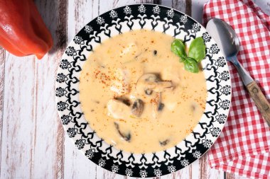 Ev yapımı tavuk ve mantar çorbası ya da Fransız usulü tavuk yahnisi, ahşap bir masada çorba kasesinde. Hava görünümü