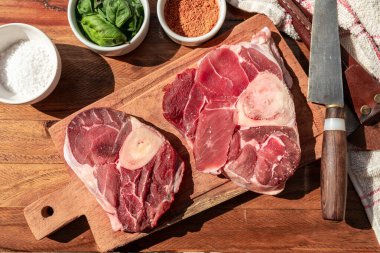 Tahta bir tahtanın üzerinde et parçalarını lezzetlendirmek için baharatlı iki biftek ossobuco. Hayvan proteini konsepti, ucuz sığır eti. Aereal görünüm.