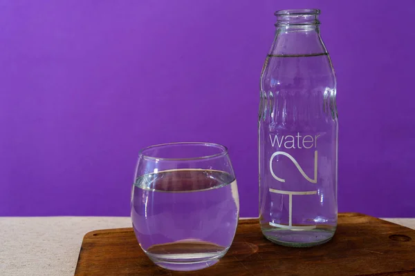 Vaso Precipitados Botella Llena Agua Purificada Fondo Violeta — Foto de Stock