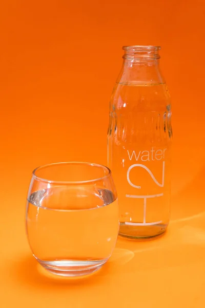 Botella Vaso Vidrio Con Agua Purificada Sobre Fondo Degradado Naranja — Foto de Stock