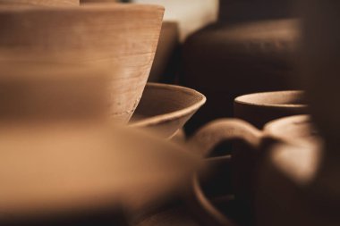 Tabakları, tabakları, kavanozları, çaydanlıkları olan raflar. Son resme kadar doğal renklerde kilden yapılmış. Kil işçiliği. Yakın plan..