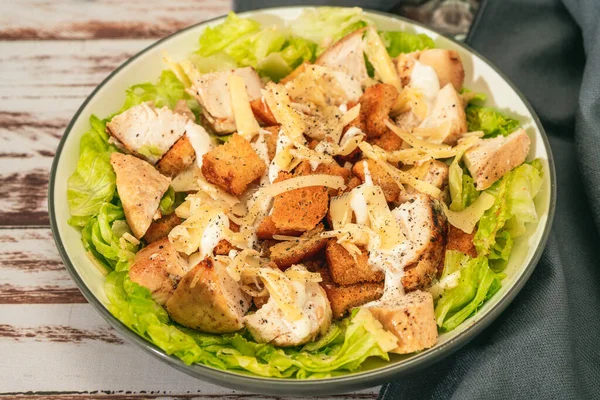 Exquisite Caesar salad with small bites of chicken and a traditional aioli sauce in a small bowl on a rustic table. High view. gourmet concept, Natural food.