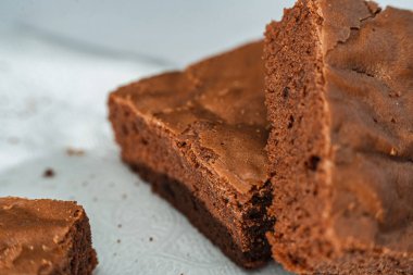 Mermer bir masada beyaz bir tabakta bir küp çikolatalı kek. Yakın çekim..