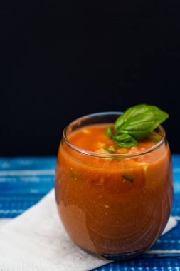 Mavi ahşap bir masada ferahlatıcı Endülüs Gazpacho ile önemli bir bardak. Yaz veya sıcak günlerde içilen soğuk sebze ve organik çorba. Dikey yönelim.