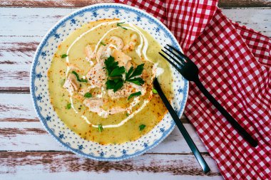 Kırsal ya da taşra tarzı ahşap masa üzerinde ev yapımı kremalı tavuk çorbası, maydanoz ve krema ile nefis bir yemek. Doğal ve basit gıda konsepti. Üst görünüm.