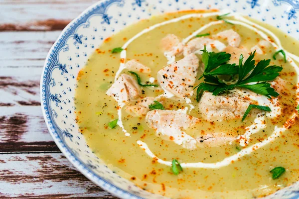 Exquisite dish with a homemade cream of poultry soup with chicken pieces, parsley and cream on a rustic or country style wooden table. Natural, healty and simple food concept. Close-up.