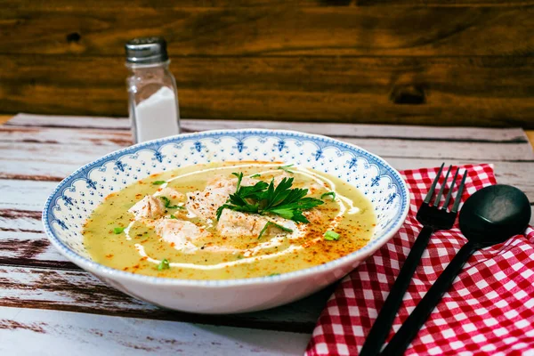Exquisite dish with a homemade cream of poultry soup with chicken pieces, parsley and cream on a rustic or country style wooden table. Natural, healty and simple food concept.
