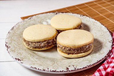 Klasik Arjantin mısır nişastası ve hindistan cevizli ve klasik bir tabakta dulce de leche alfajores. Yüksek görünüm