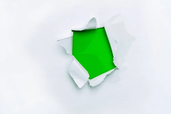 A hole in white paper with torn edges and a green isolated background inside, Ripped grenn and white paper, copy space
