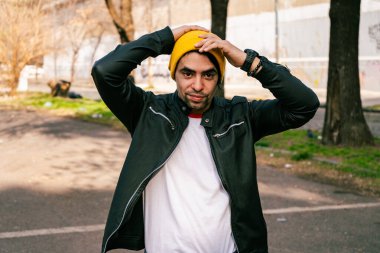 A Latin young man with yellow wool cap holding his head. Concept of modernity.