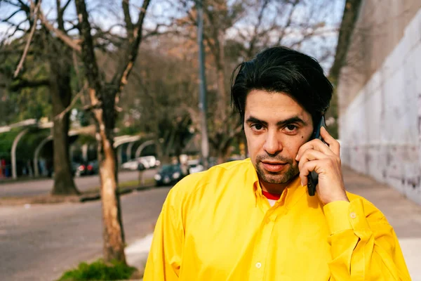 Портрет Красивого Латинского Молодого Человека Жёлтой Рубашке Разговаривающего Телефону Улице — стоковое фото