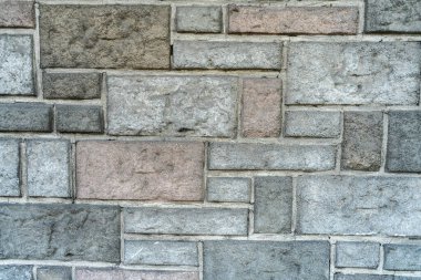 A Background arrangement of stones or slabs of different shapes and colors on a wall.