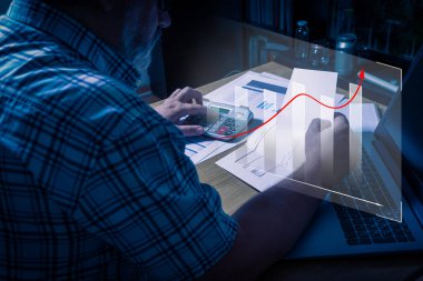 Beyaz bir erkek yatırım performansını analiz ediyor. Bir histogramın aşırı çizilmiş grafiği ve kırık çizgi ay ay.