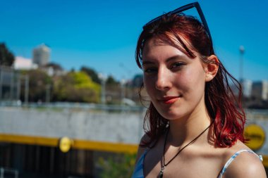 Güneşli bir günde mutlu bir ifade takınan kızıl saçlı genç bir kadının yakın çekimi. Uzayı kopyala Peyzaj yönelimi.