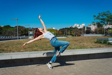 Sokaklarda zıplamalar ve taklalar atarak mutlu bir şekilde dans eden genç ve güzel Latin. Eğlence kavramı, sokak dansı, hip hop, gençlik.