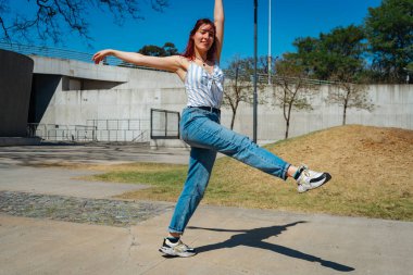 Sokaklarda zıplamalar ve taklalar atarak mutlu bir şekilde dans eden genç ve güzel Latin. Eğlence kavramı, sokak dansı, hip hop, gençlik.