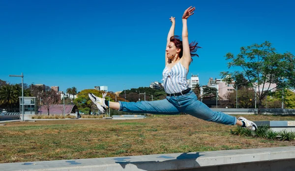 Beautiful young latina dancing happily in the street while partying with jumps and somersaults. Concept of joy, street dance, hip hop, youth.