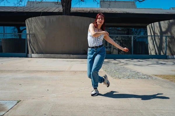 Beautiful young latina dancing happily in the street while partying with jumps and somersaults. Concept of joy, street dance, hip hop, youth.