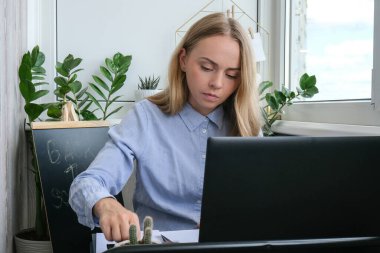 Genç bayan öğretmen masada oturuyor ve evde dizüstü bilgisayar kullanıyor. Eğitime geri dön. Öğrenci çevrimiçi ders alıyor. Mesafe öğrenme. Sınav hazırlığı