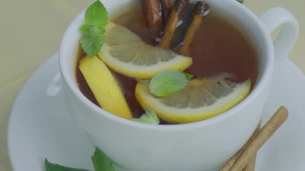 Černý a zelený čaj s citronem, skořicovými tyčinkami a mátovými listy. Horký drink. Zdravá melissa čaj přírodní organické aromatické nápoje v šálku. Léto, podzimní zimní nápoj. — Stock video