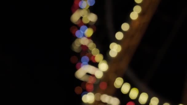 Defocused bright lights flash at a fun carnival at night. Amusement Park Bokeh Lights at Night — Stock Video