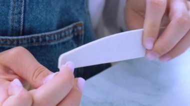 Kadın eli manikür yapıyor. Dosya ve şekil çivi bakımı, kişisel bakım. Evde otururken tek başına manikür yap. Diy. Manikür araçları