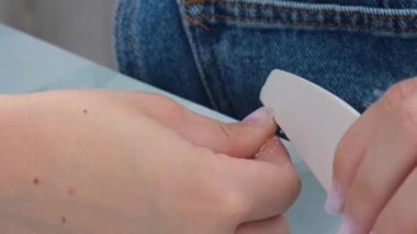 Kadın eli manikür yapıyor. Dosya ve şekil çivi bakımı, kişisel bakım. Evde otururken tek başına manikür yap. Diy. Manikür araçları