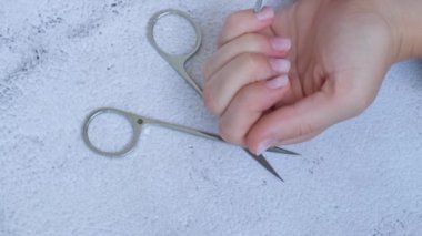 Kadın eli manikür yapıyor. Tırnak derisini söker, özen gösterir. Evde otururken tek başına manikür yap. Diy. Boya, dosya ve oval şekilli tırnaklar.
