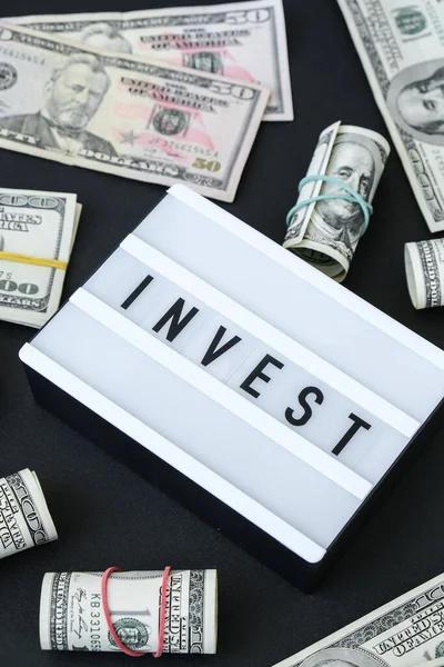 米ドル紙幣の周りの黒い文字で単語InvestとLightboxボード ビジネス 現金請求書 富と繁栄の財政の事業予算 受動的所得 — ストック写真