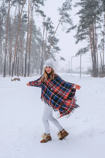 Dans eden kadın ormanda şapka ve panço giyerek geziyor, boho ve gezgin şehvet stili. Kış geliyor, ilk kar yağışı — Stok fotoğraf