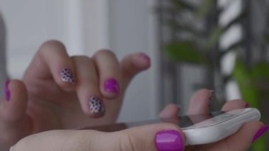 Cep telefonu tutan zarif pembe tırnaklı manikürlü kadın elleri. Akıllı telefon teknolojisi. Modern moda tasarım manikürü. Jel tırnaklar. Cilt bakımı. Güzellik tedavisi. Tırnak bakımı. Moda renkleri