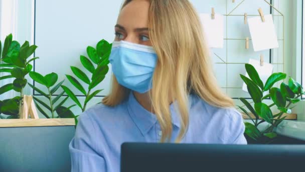 Giovane donna che lavora su un computer in un ufficio moderno. Donna d'affari che lavora al suo portatile indossando una maschera medica. tutoraggio conferenza online. Studente di educazione online — Video Stock