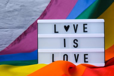 Işıkkutusu ve mesajı olan gökkuşağı bayrağı aşktır. İpek kumaştan yapılmış gökkuşağı lgbtq bayrağı. LGBTQ gurur ayının sembolü. Eşit haklar. Barış ve özgürlük. LGBTQ topluluğunu destekle