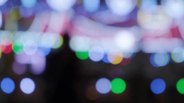 Odaklanamayan parlak ışıklar gece bir karnavalda yanıp sönüyor. Lunapark Gece Bokeh Işıkları