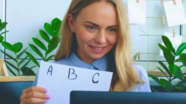 Guru perempuan muda duduk di meja dan menggunakan laptop mengajar alfabet di rumah. Pendidikan Kembali ke sekolah. Pelajar kelas online. Belajar jarak jauh. Persiapan ujian — Stok Video