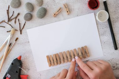 Adım adım. Üst Manzara. İşlemci çocuk işi. Kendin yap Mutlu Noeller geyiği çakıl taşlarından, deniz taşlarından, mandallardan ve beyaz arka planda dallardan oluşan kartpostalda. Doğal Eko tarzı diy. Hediye fikri..