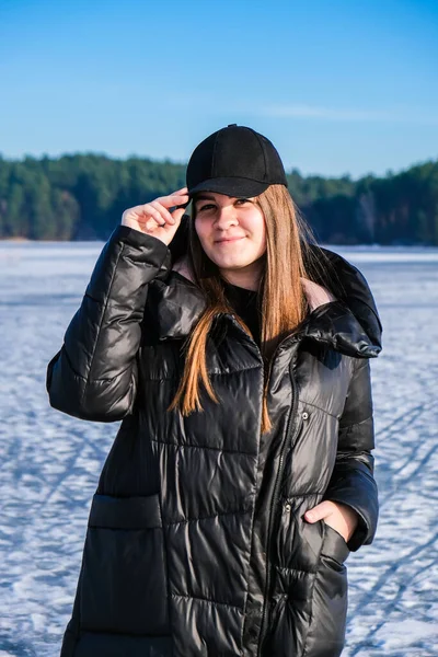 年轻的女性微笑着看着雪景中的相机 快乐的嬉皮士女孩与嘻哈温暖的冬季衣服 呆在冰冻的河里 年轻迷人的微笑女子冬季肖像 — 图库照片