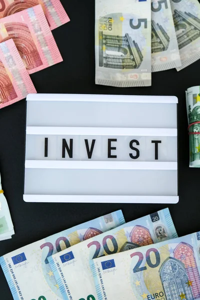 ユーロ紙幣の周りの黒い文字で単語InvestとLightboxボード ビジネス 現金請求書 富と繁栄の財政の事業予算 受動的所得 — ストック写真