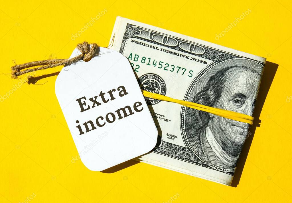 Dollars cash money and paper note with text written EXTRA INCOME. Concept of financial planning. Make more extra money from parttime side hustle or second job. Startup investment