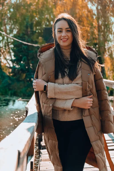 Красивая брюнетка в осеннем парке. Улыбающаяся молодая женщина тысячелетия в пальто, наслаждающаяся солнечной погодой осенью. Внешний портрет — стоковое фото