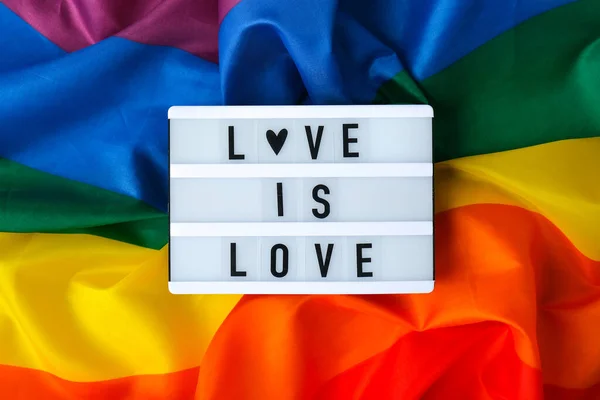 虹の旗とライトボックスとテキストの愛は愛です シルク素材で作られたレインボーLgbtqフラグ Lgbtqプライド月間のシンボル 平等な権利 平和と自由 Lgbtqコミュニティ — ストック写真