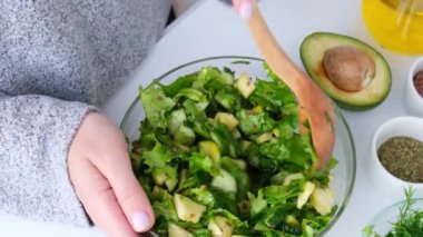 Kadın taze yeşil sebze salatasıyla otları karıştırıyor. Çiğ gıda konsepti. Vejetaryen menüsü. Sağlıklı beslenme ya da vejetaryen yemekleri pişirmek. Adım adım tarif.