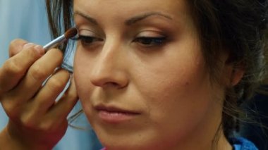 Makyaj sanatçısı genç bir kadının gözlerine makyaj yapar. Geline makyaj yapan profesyonel bir makyöz. Yabani ot