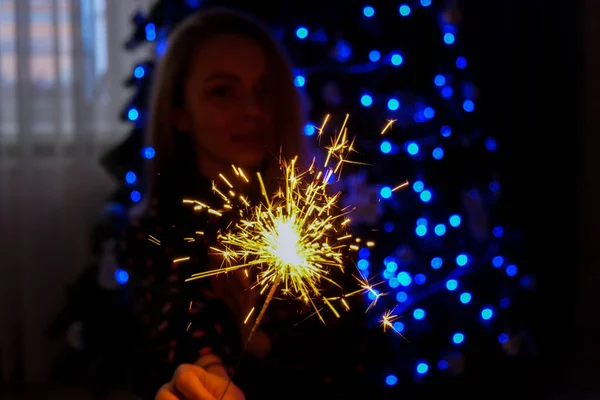 快乐的年轻女人坐在圣诞树旁 手里拿着一杯香槟和一盏灯 新年派对的庆祝活动圣诞寒假新年前夕 — 图库照片